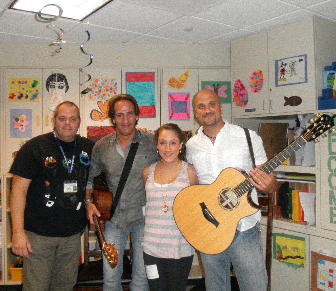 Four people holding guitars in classroom